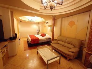 姬路ホテル カーシュ Cache 男塾ホテルグループ的酒店客房配有床、沙发和桌子。
