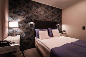 罗瓦涅米阿克努斯酒店的一间卧室配有一张床,墙上贴有壁纸