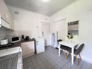 悉尼Budget 1 bedroom unit near Maroubra Beach的厨房配有桌子和白色冰箱。