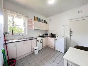 悉尼Budget 1 bedroom unit near Maroubra Beach的厨房配有白色橱柜、水槽和冰箱。