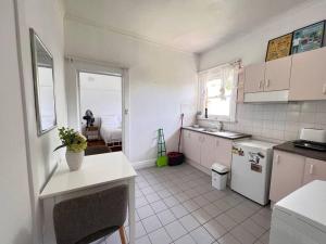 悉尼Budget 1 bedroom unit near Maroubra Beach的厨房配有白色家电,铺有白色瓷砖地板。