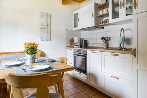 雷根Bayerwaldchalet的厨房配有白色橱柜和木桌