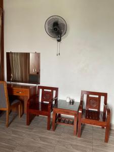 海阳Trúc Lâm hotel的客房设有椅子、桌子和风扇。