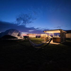 维特蒙德Lodge Camp Harlesiel direkt am Wattenmeer的帐篷和吊床(晚上在田野上)
