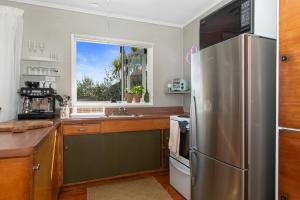 旺阿雷Kereru Cottage - Matapouri Holiday Home的厨房配有不锈钢冰箱和窗户