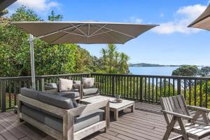 旺阿雷Kereru Cottage - Matapouri Holiday Home的庭院配有两把椅子和一把遮阳伞