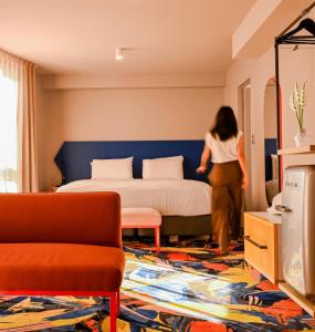 悉尼Adge Hotel and Residence - Adge Queen - Australia的一位女士走进一间酒店的房间,房间内设有一张床
