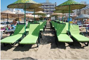 艾瓦勒克莫斯塔尔酒店的海滩上一排绿色沙滩椅和遮阳伞