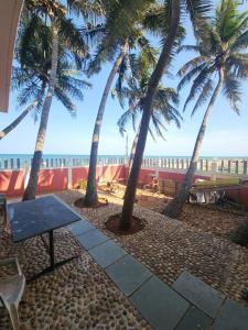 SingānallūrParadise Harmony Beach Resort的棕榈树海滩上的野餐桌