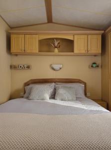 TossideVacanza Static Caravan的一间卧室配有一张大床和木制床头板