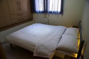 塞萨洛尼基Elpida's houses 1 Private parking Near city centre的一间卧室配有一张带白色床单的床和一扇窗户。