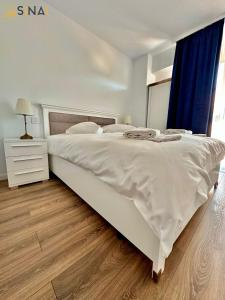 锡纳亚SINAI APH Apartments的卧室铺有木地板,配有一张大型白色床。