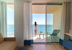 贝纳尔马德纳Hotel Benalmadena Beach的站在一个眺望海洋的阳台上的女人