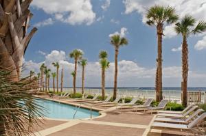 巴拿马城海滩Sterling Reef Beach Resort的棕榈树和海滩的游泳池