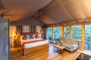 奈尼塔尔Ayar Jungle Resort的帐篷内一间卧室,配有一张床和一张沙发