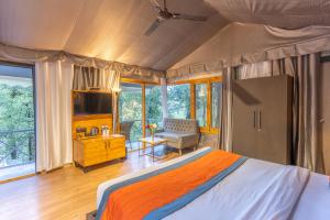 奈尼塔尔Ayar Jungle Resort的一间卧室配有一张床、一张书桌和一台电视