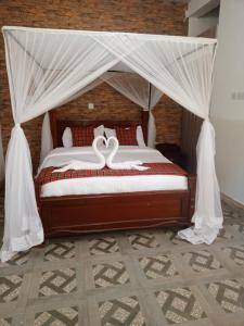 基苏木Queen's Way Resort的卧室配有带白色窗帘的天蓬床
