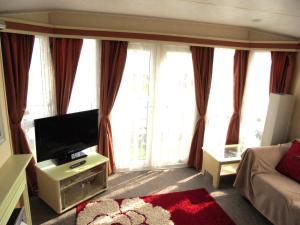 滨海萨顿Sapphire 8 Berth panel heated Towervans的客厅配有平面电视和沙发。