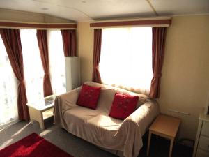 滨海萨顿Sapphire 8 Berth panel heated Towervans的客厅配有带2个红色枕头的沙发