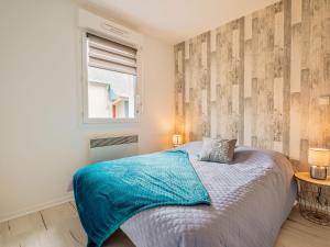 普勒尔蒂Apartment Résidence les Caps Horniers 2 by Interhome的一间卧室配有一张带蓝色毯子的床和窗户。