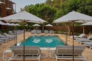 圣米格尔港The Club Cala San Miguel Hotel Ibiza, Curio Collection by Hilton, Adults only的一个带躺椅和遮阳伞的游泳池
