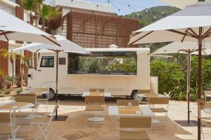 圣米格尔港The Club Cala San Miguel Hotel Ibiza, Curio Collection by Hilton, Adults only的停放在椅子和遮阳伞旁边的食品车