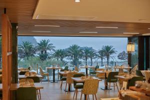 圣米格尔港The Club Cala San Miguel Hotel Ibiza, Curio Collection by Hilton, Adults only的一间带桌椅的海景餐厅
