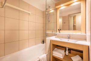 马赛Comfort Aparthotel Marseille Prado的一间带水槽、浴缸和镜子的浴室