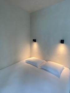 根特Edville Studio的一张带两个枕头和灯的白色床