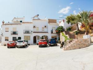 弗里希利亚纳Tipica Casa En Frigiliana con patio y terraza的一座大型白色房子,停车场有车辆停放