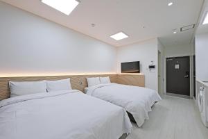 束草市World Sky Residence Hotel的配有白色床单的酒店客房内的两张床