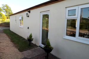 阿斯克Glenview Lodge accommodation, Monmouthshire的白色房子的一侧有窗户和植物