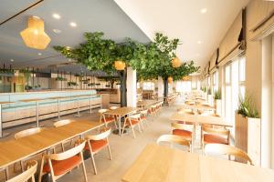 博尔滕哈根BEECH Resort Boltenhagen的餐厅设有木桌和椅子,种有植物