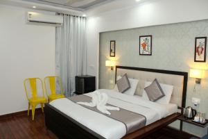 巴雷利Hotel Krishna Residency Bareilly Near Ashish Royal Park的一间卧室配有一张大床和两张黄色椅子