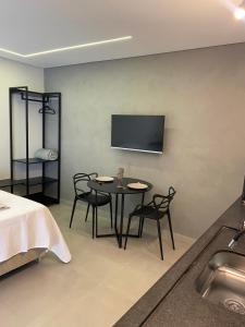 阿拉沙Loft de luxo的一间设有桌椅和墙上电视的客房