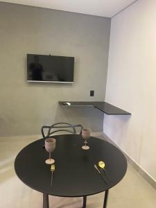 阿拉沙Loft de luxo的一张带两杯酒杯的黑桌和一台电视