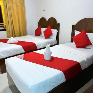 桑托斯将军城Offshore Hotel的配有红色和白色枕头的客房内的两张床