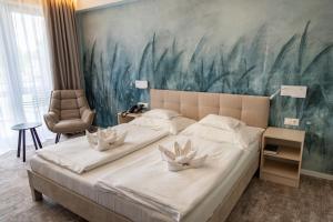 豪伊杜索博斯洛Hotel Atlantis Wellness & Conference的卧室配有一张大床,墙上挂有绘画作品