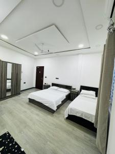 FuvahmulahNoya Inn的大房间设有两张床,拥有白色的墙壁