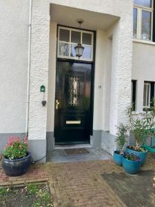 阿珀尔多伦Luxe kamer in stadsvilla, gratis parkeren!的一座种植盆栽植物的房子的黑色前门