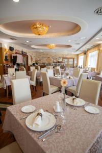 豪伊杜索博斯洛Hotel Atlantis Wellness & Conference的用餐室配有白色的桌子和白色的椅子