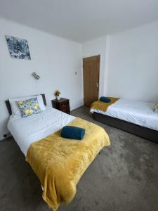 卢顿Immaculate 3-Bed House in Luton的一间卧室配有两张带黄床单的床