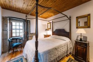 布拉加Casa da Pedra Cavalgada的一间卧室配有一张天蓬床和一把椅子