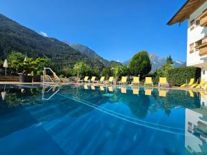 迈尔霍芬埃登勒汗酒店的一个带椅子的游泳池,背景是山脉
