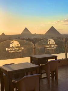 开罗The Horizon Pyramids View的两把桌子和椅子,位于一座金字塔建筑的顶部