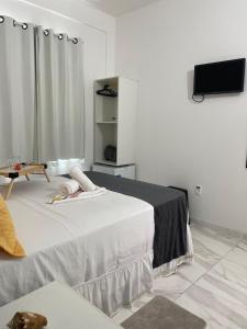 甘博阿Estrela Premium Pousada的白色的客房配有床和平面电视。