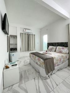 甘博阿Estrela Premium Pousada的一间卧室配有一张大床和电视