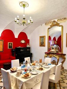 卢切拉B&B Palazzo Lombardi的一间用餐室,配有一张桌子、白色的椅子和红色的墙壁