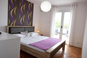巴尔Apartmani Novkovic的一间卧室配有一张大床和紫色毯子