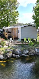 雷日卡普费雷Mobil home tout confort Camping Les VIVIERS CAP FERRET的水边的绿色椅子房子